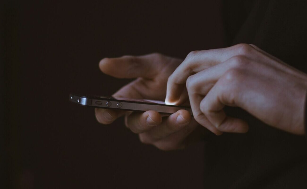 Zwei Hände auf schwarzem Hintergrund, die am Smartphone scrollen