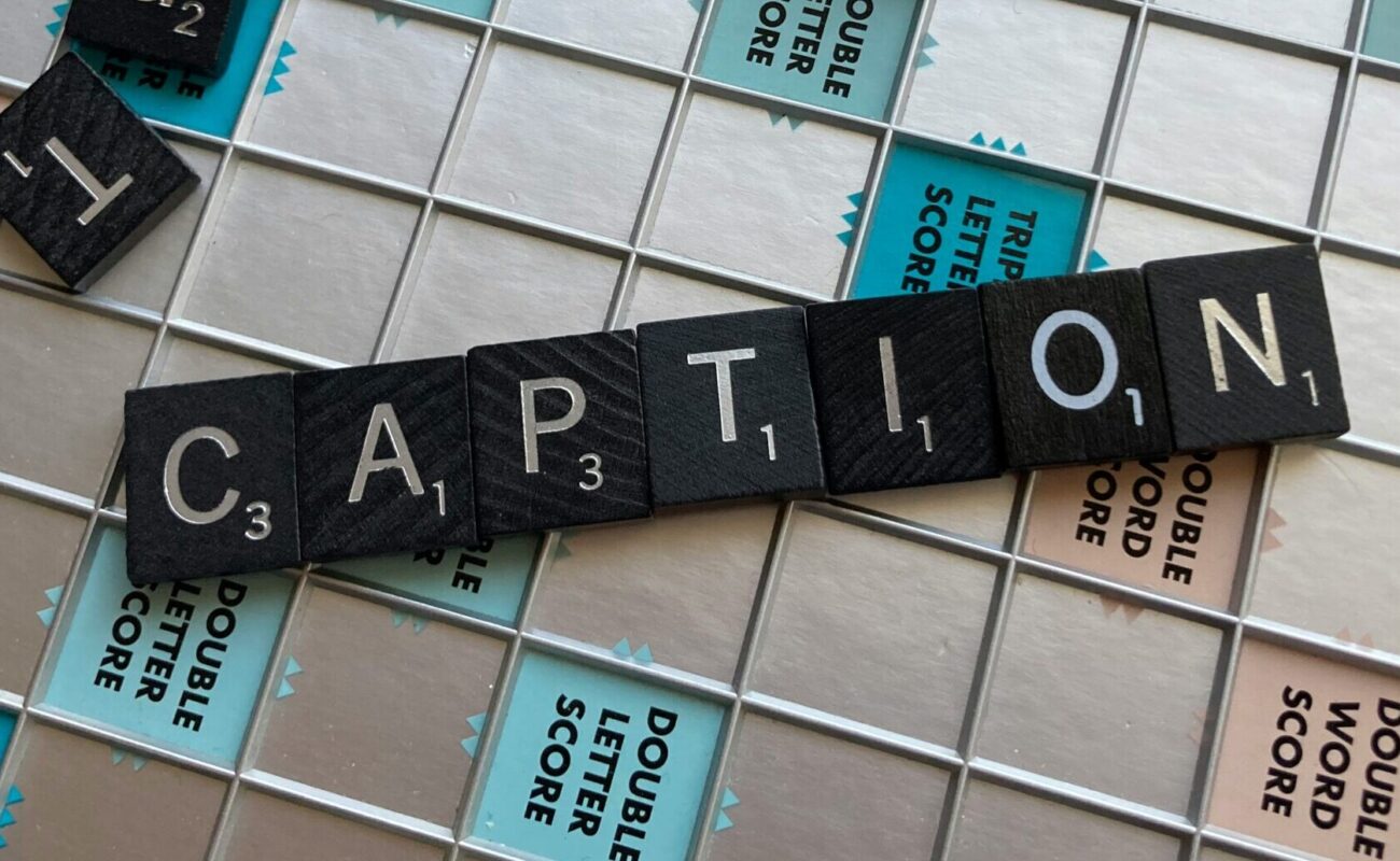 Wort "Caption", das aus Scrabble-Steinen gebaut ist und auf dem Spielbrett liegt