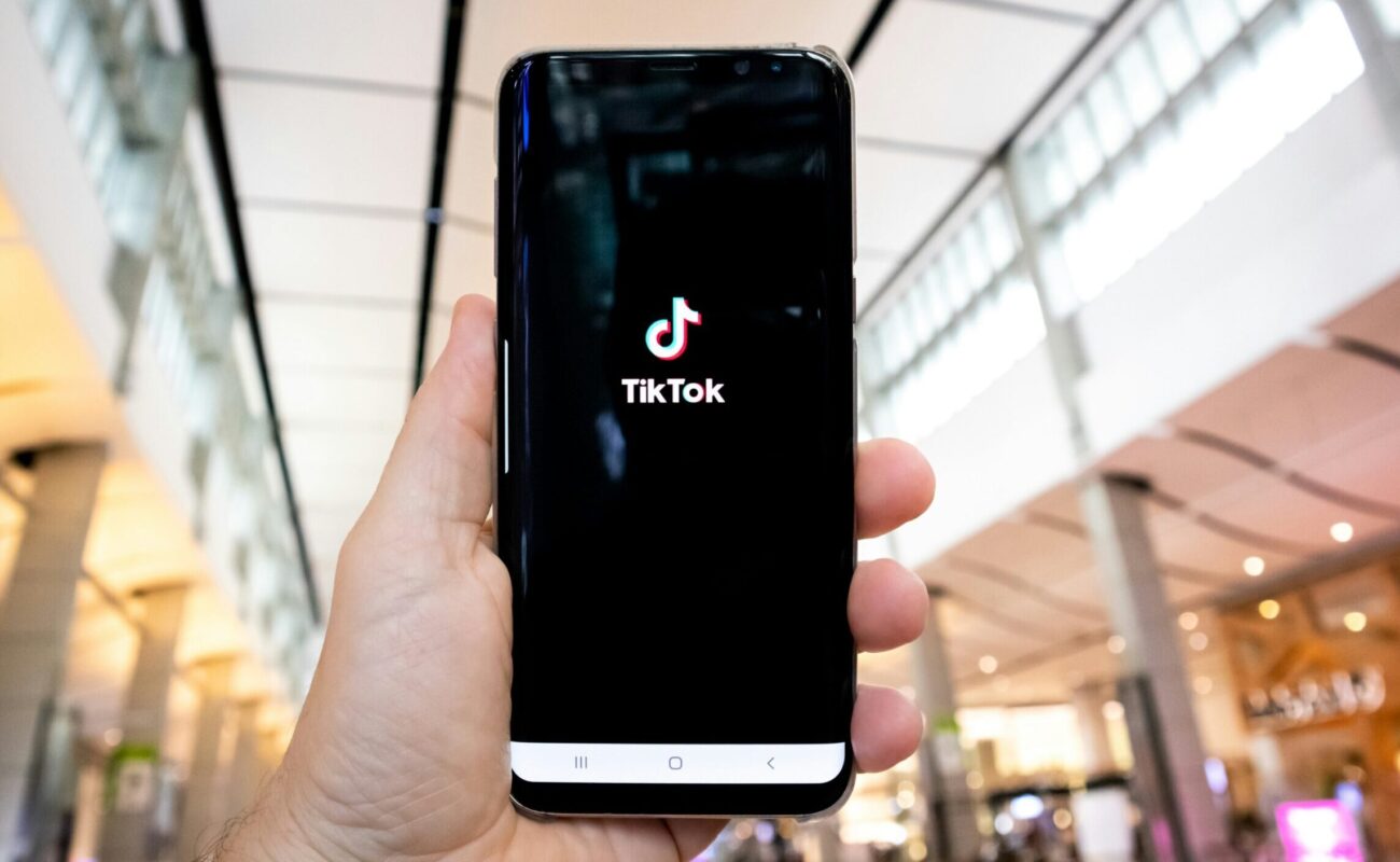 Hand hält Smartphone in die Höhe, auf dem die Tiktok App geöffnet wird