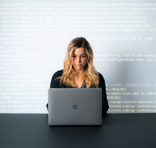 Person arbeitet konzentriert am Notebook, mit Code-Zeilen im Hintergrund