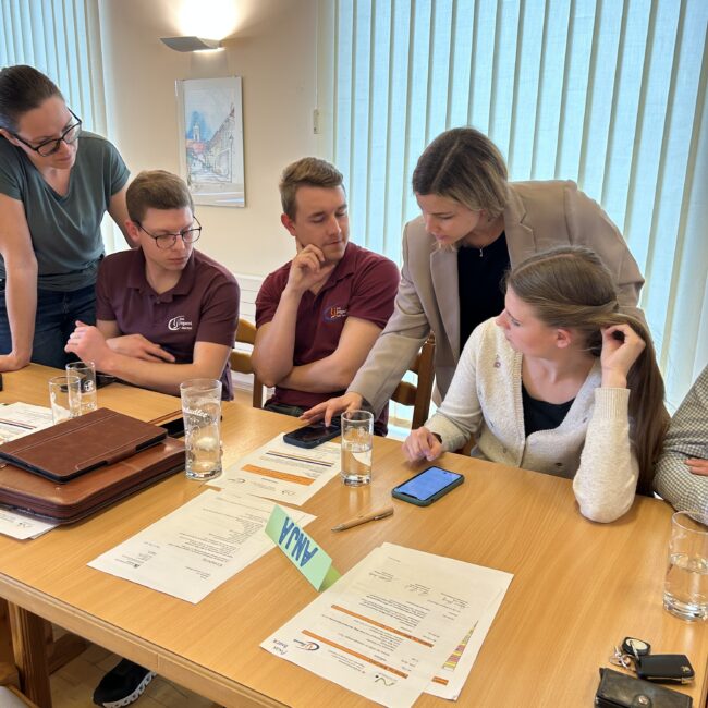 Eine Person zeigt vier weiteren Personen etwas auf einem Smartphone