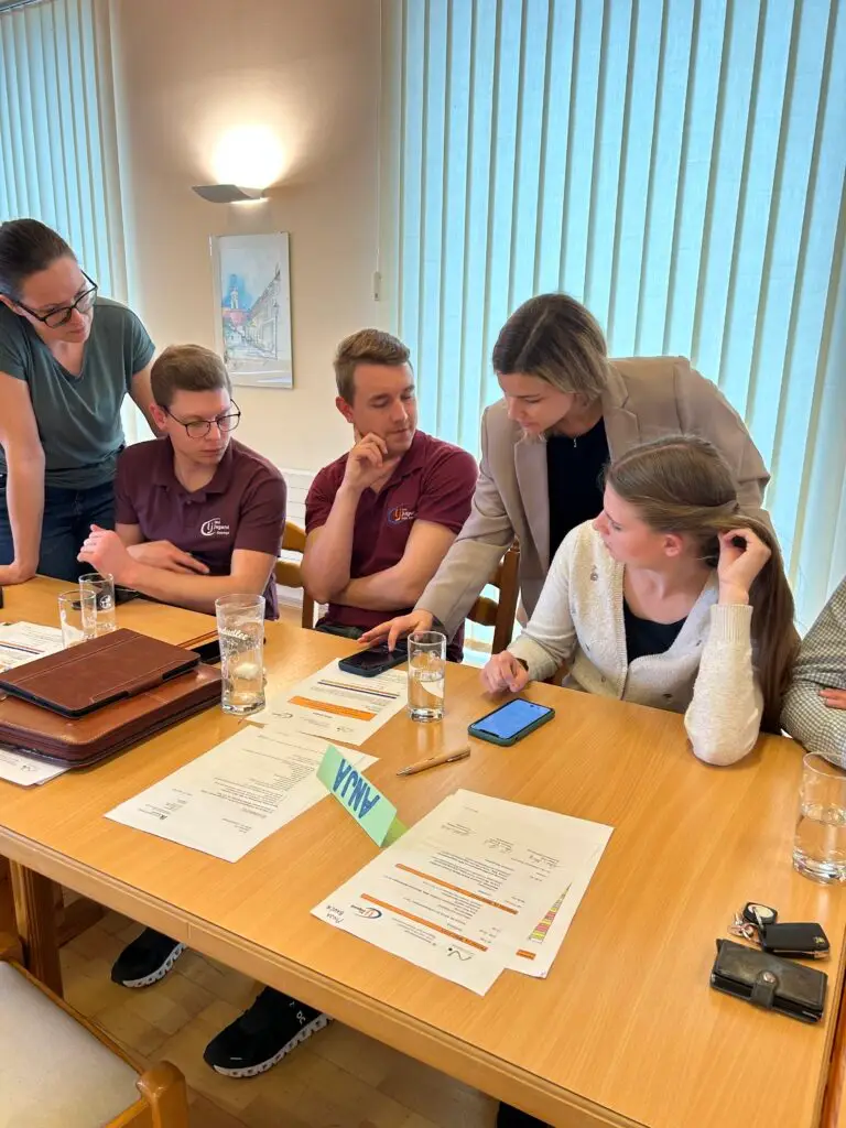 Eine Person zeigt vier weiteren Personen etwas auf einem Smartphone