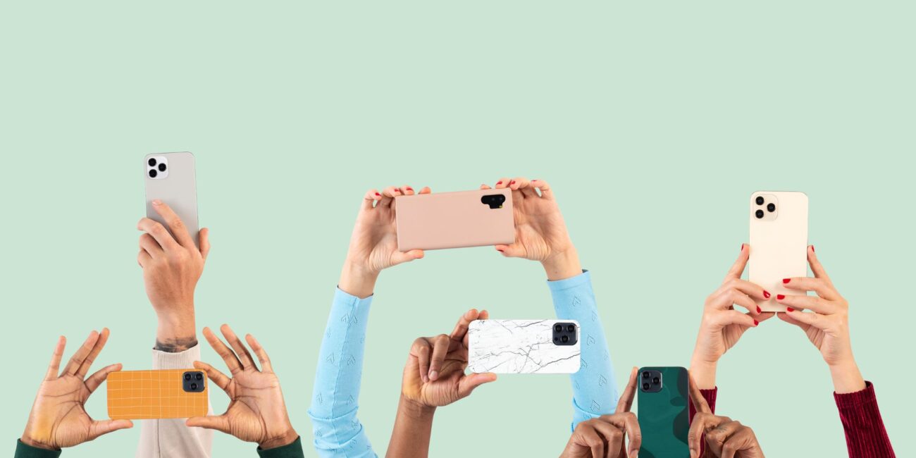 Mehrere Hände mit Smartphones in bunten Hüllen werden in die Höhe gehalten, Hintergrund in Pastellgrün.