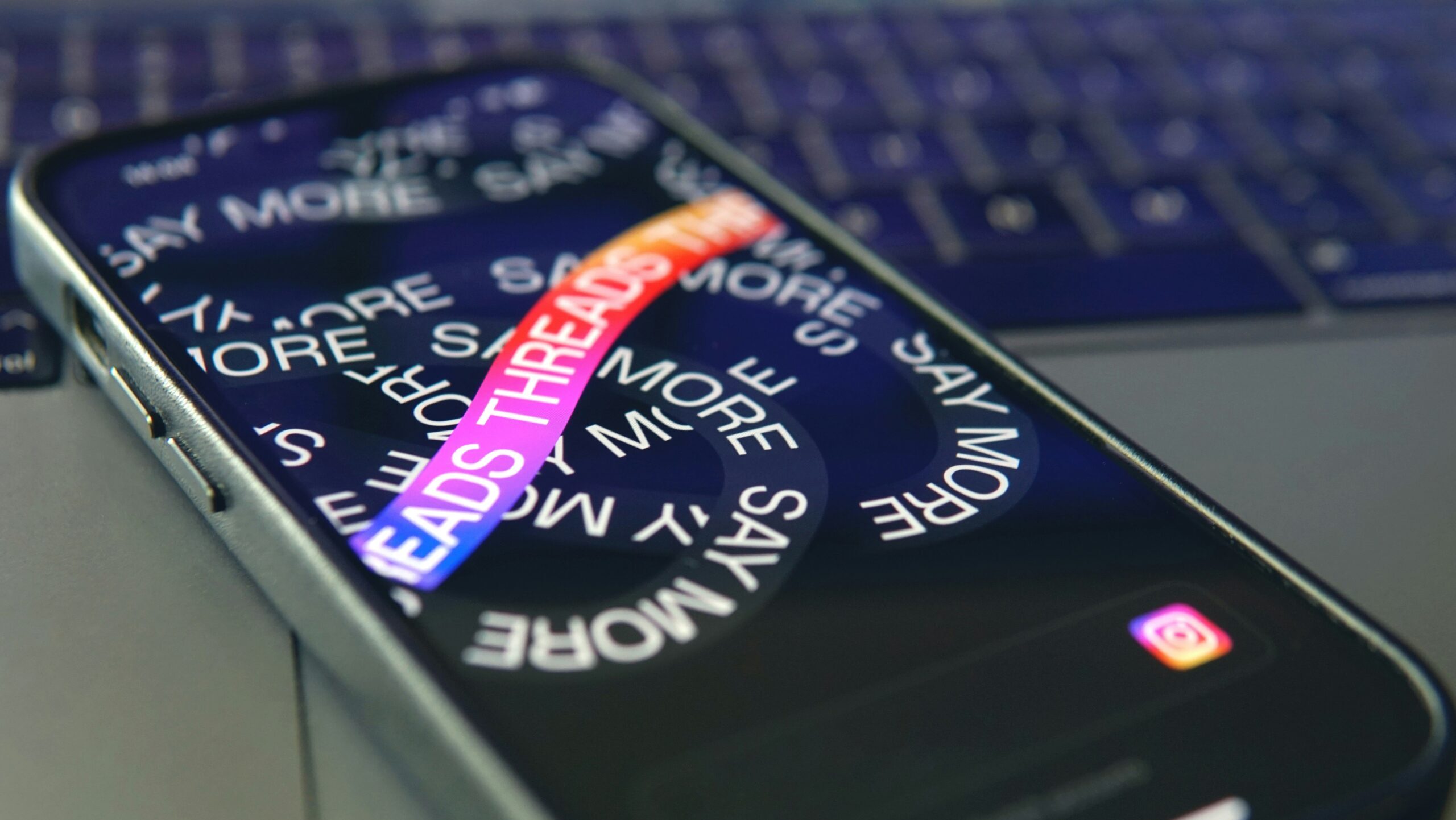 Smartphone mit geöffneter Threads-App auf einem Laptop liegend.