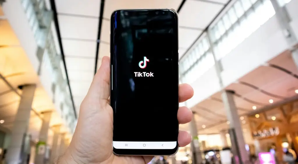 Hand hält ein Smartphone mit geöffneter TikTok-App.