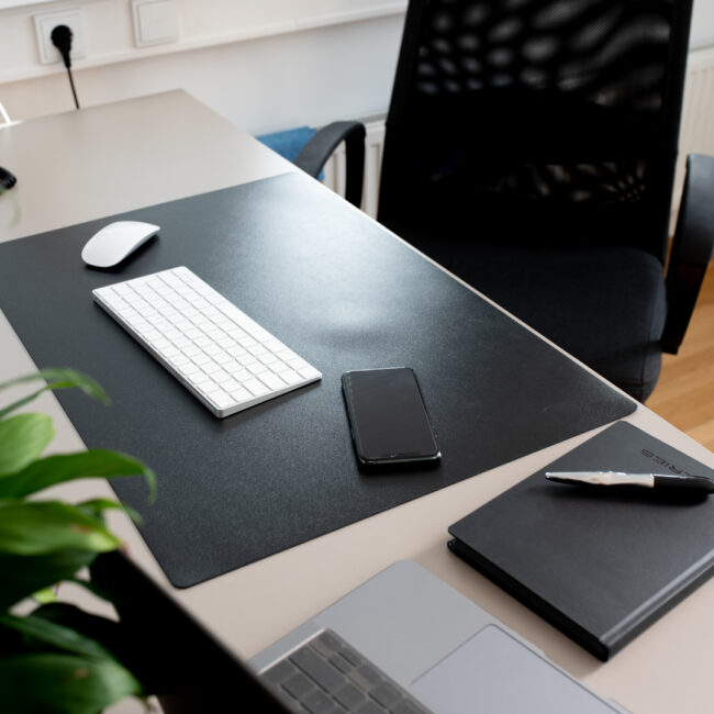 Bürotische mit verschiedenen Utensilien wie Maus, Tastatur, Smartphone, Notizblock & Stift