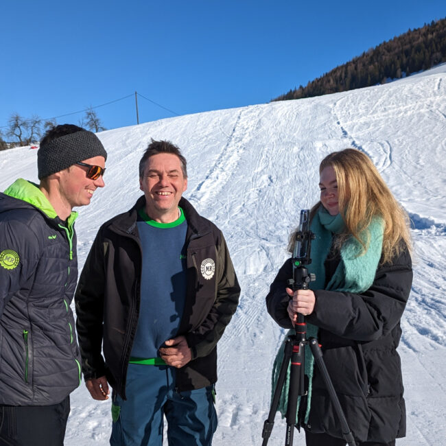 3 Personen stehen lächelnd auf einer Skipiste