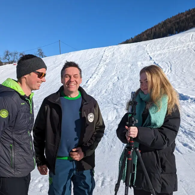 3 Personen stehen lächelnd auf einer Skipiste