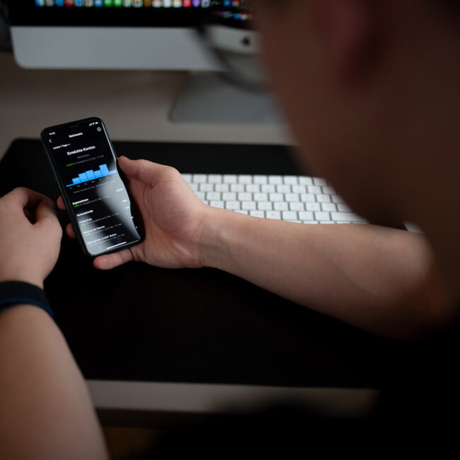 Person hält Smartphone mit sichtbarer Statistik-Anzeige in der Hand.