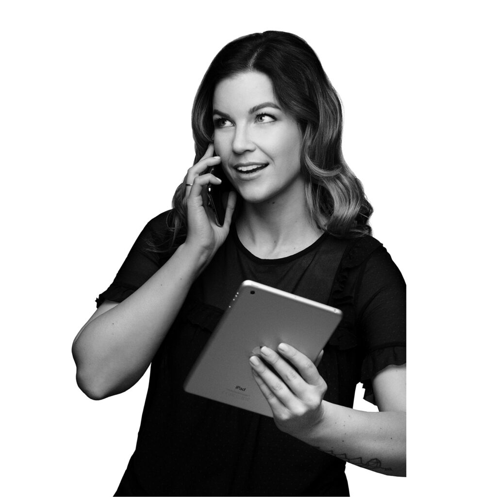 Schwarz-weiß Porträt einer Frau, die telefoniert und gleichzeitig ein Tablet in der Hand hält.